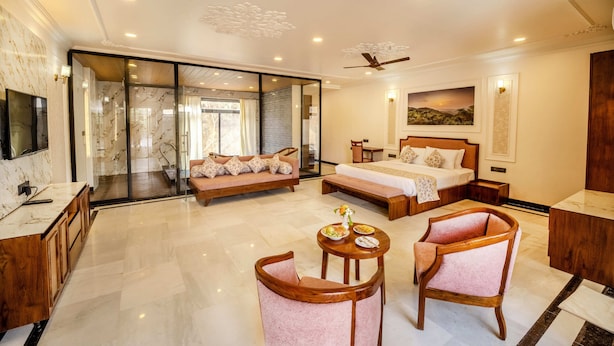 A hotel room with a large bed, a sofa, a desk, and a TV. - Kavish Holiday Hill Resort (Udaipur)