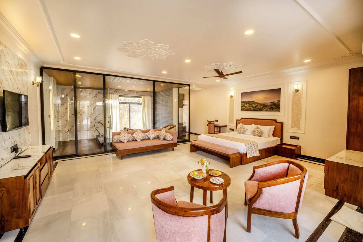 A hotel room with a large bed, a sofa, a desk, and a TV.
