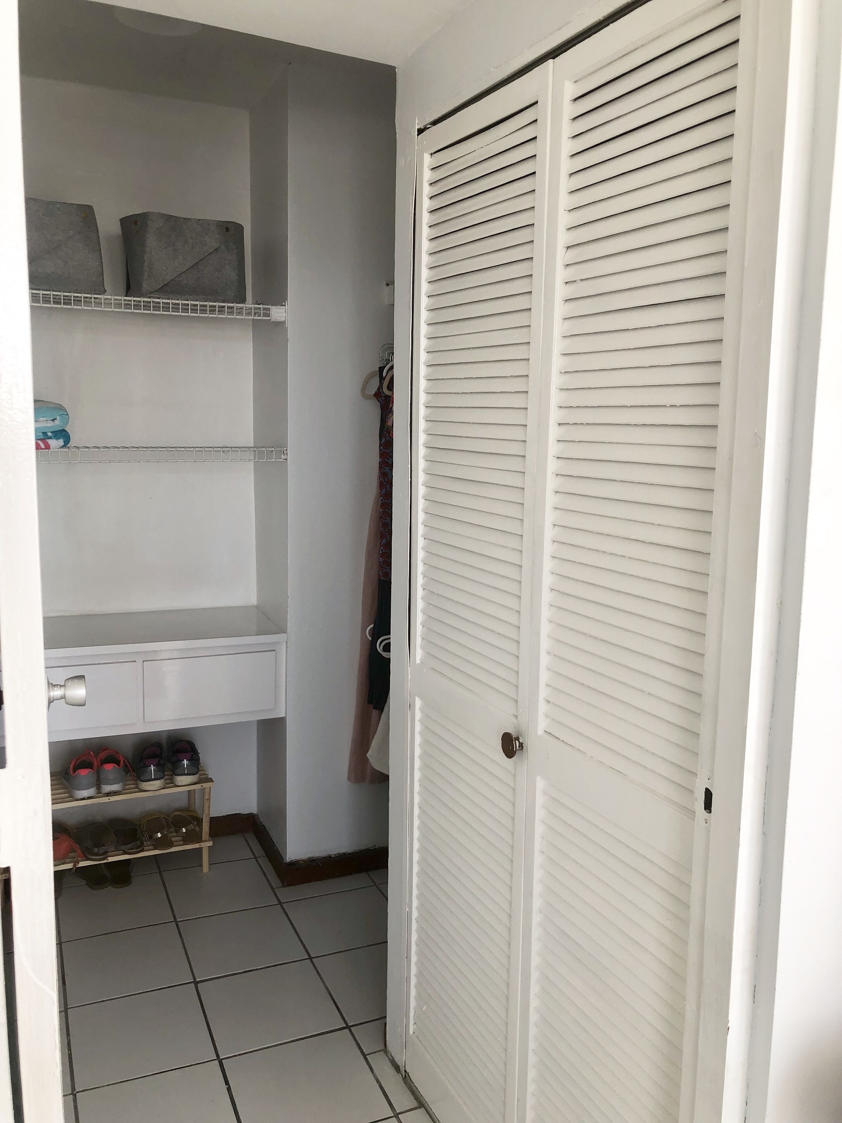 Un placard avec des étag ères, un porte-chaussures et une porte à panneaux ajourés.