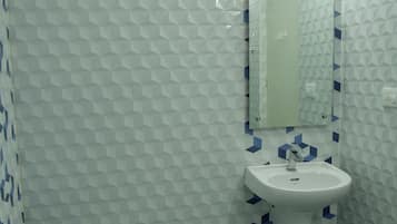 A bathroom with a toilet, sink, and mirror.