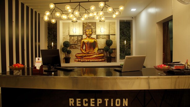 A reception desk with a golden Buddha statue, a laptop, and a bowl of flowers.