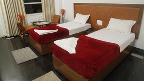 A hotel room with two beds, a desk, and a chair.
