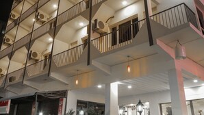 A multi-story hotel with balconies, air conditioning units, and a well-lit entrance.