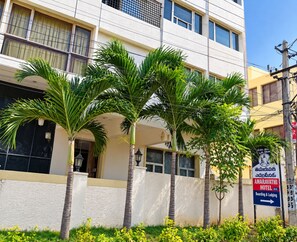 Um edifício com vários andares, uma placa indicativa do Hotel Amaravathi e diversas palmeiras na frente.