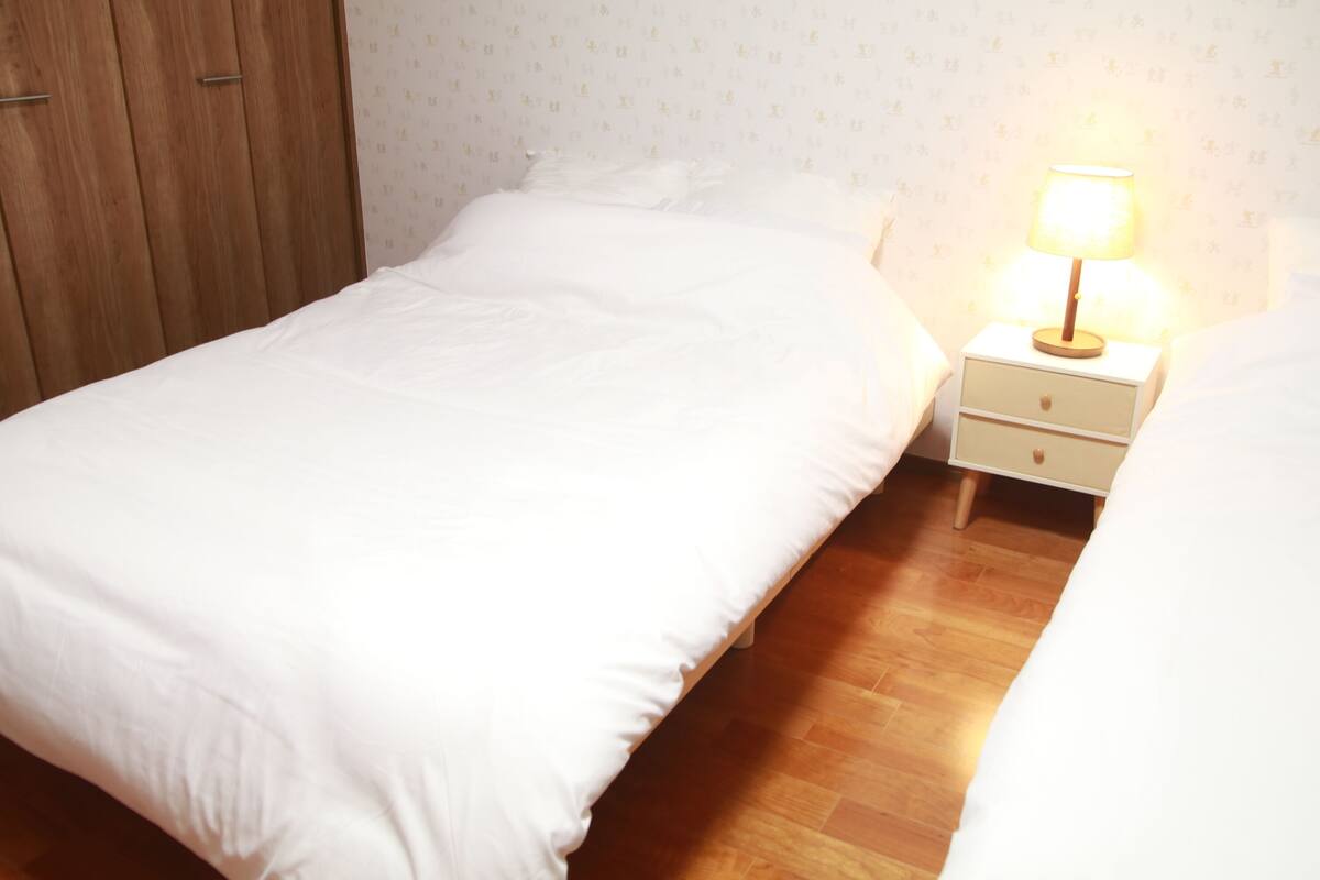 A bedroom with a bed, wooden wardrobe, and a bedside table with a lamp.