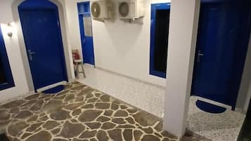 Una habitación con piso de diseño de piedra, puertas azules y paredes blancas.