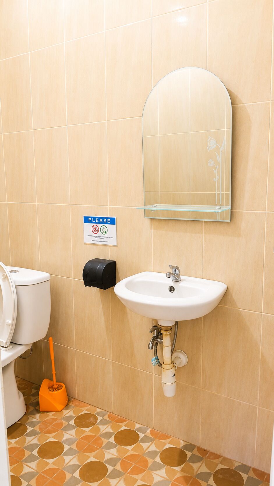 A bathroom with a white sink, a mirror, a toilet, and a mop.