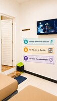 Habitación de hotel con televisión, cartel que indica baño privado y suite, sin ventana al exterior y un cesto de basura.