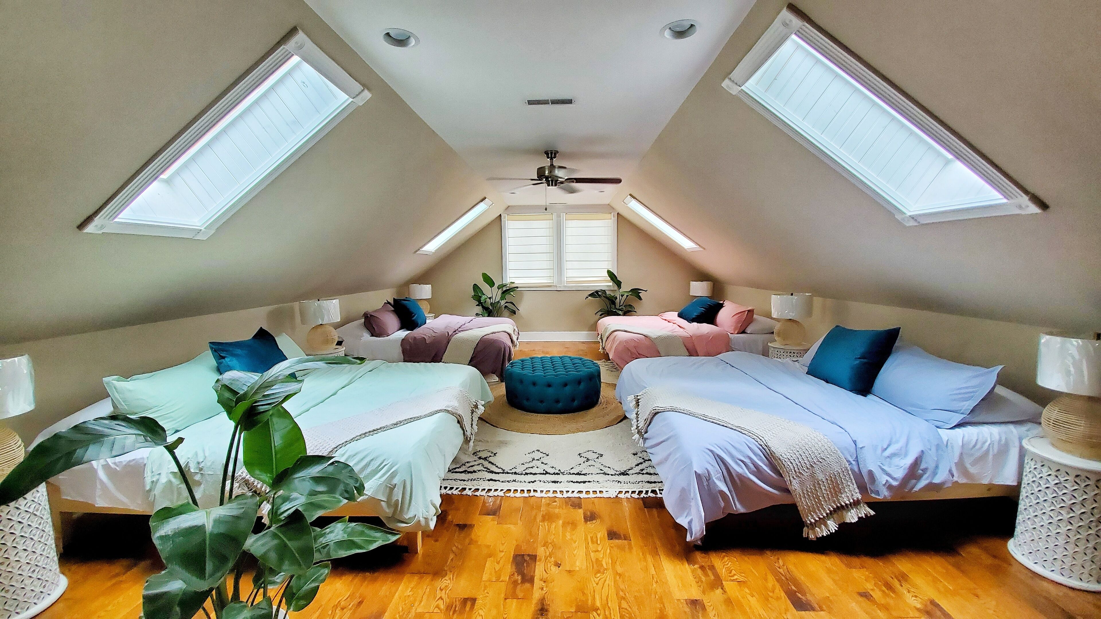 A cozy attic bedroom with two beds, a ceiling fan, and skylights.