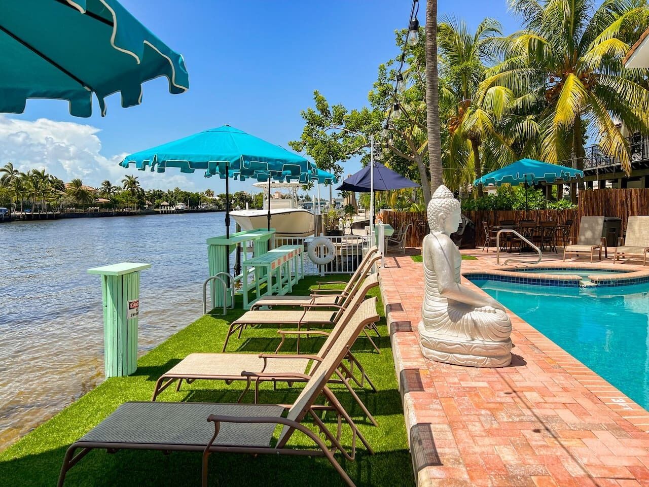 A poolside area with lounge chairs, umbrellas, and a statue.