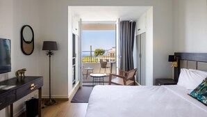 A hotel room with a bed, a desk, a chair, a TV, and a balcony with a view. - La villa (Antibes)