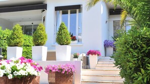 A multi-story hotel with a central entrance, potted plants, and a staircase leading to the upper floors. - La villa (Antibes)