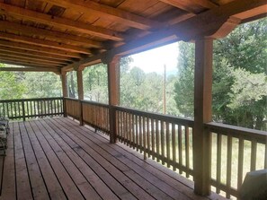 A wooden deck with a railing, overlooking a forested area.