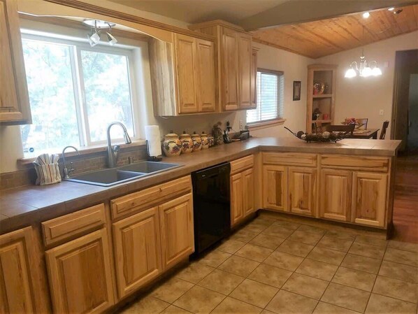 A kitchen with wooden cabinets, a dishwasher, and a window providing natural light.