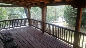 A wooden deck with a railing, surrounded by trees. - Pine Mountain Retreat (Ruidoso)