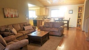 A living room with two sofas, a coffee table, and a kitchen in the background. - Pine Mountain Retreat (Ruidoso)