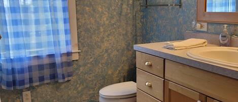 A bathroom with a toilet, a sink with a mirror, and a towel.