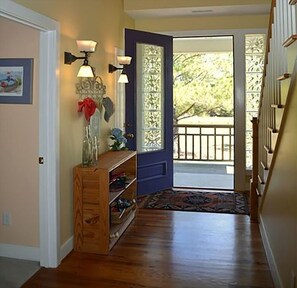 Enter a beautifully appointed hallway with a decorative glass panel door, a wooden bench, and a stylish light fixture.