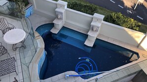A swimming pool with steps, a glass balustrade, and a patio area with a table and chairs. - Supersized whole floor Residence Near Manly (Balgowlah)