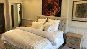 A bedroom with a large bed, a nightstand, a framed rose painting, and a framed abstract painting on the wall. - Supersized whole floor Residence Near Manly (Balgowlah)