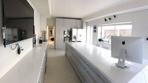 A modern kitchen with white cabinetry, a large island, and an Apple desktop computer. - Supersized whole floor Residence Near Manly (Balgowlah)