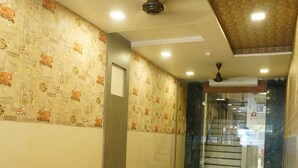 A lobby with a black leather sofa, a glass staircase, and a patterned wall. - Sharda residency (Mumbai)