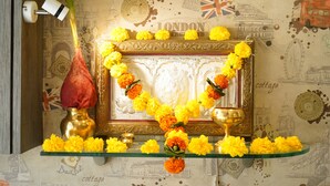 A wall with a decorative frame, a brass vase, and a glass shelf with flowers. - Sharda residency (Mumbai)