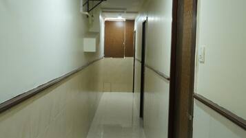 A long, narrow hallway with white walls and a tiled floor.