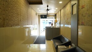 A hotel lobby with a reception desk, a waiting area with leather seating, and patterned walls. - Sharda residency (Mumbai)