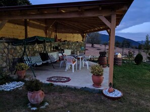 Un área de estar al aire libre cubierta con paredes de piedra, una mesa, sillas y plantas en macetas.