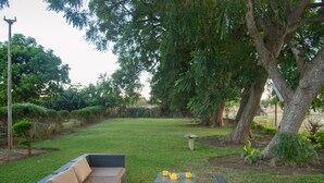 A backyard with a dark wicker sofa and a small table with yellow cups.
