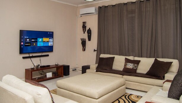 A living room with a flat-screen TV, a sofa, a coffee table, and a decorative wall piece.