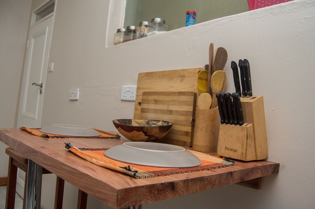 A kitchen counter with a wooden cutting board, a bowl, a knife block, and a spice rack.