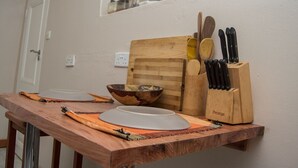 A kitchen counter with a wooden cutting board, a bowl, a knife block, and a spice rack.