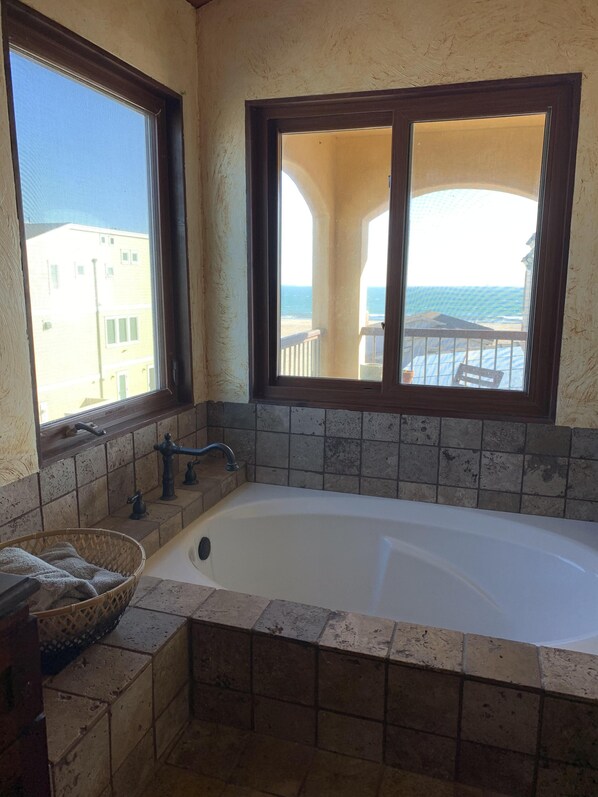 A bathroom with a bathtub, a window, and a view of the ocean. - Luxurious at the Beach!  (Surfside)