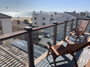A rooftop terrace with wooden chairs, solar panels, and a view of the beach and ocean. - Luxurious at the Beach!  (Surfside)