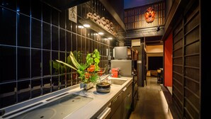 A narrow kitchen with a modern stove, a sink, and a small countertop with a potted plant. - Miyagawacho Samurai Machiya, Miyagawacho Samurai Machiya (京都市)