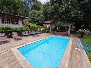 Ein rechteckiger Pool mit einer Holzterrasse und Liegestühlen.