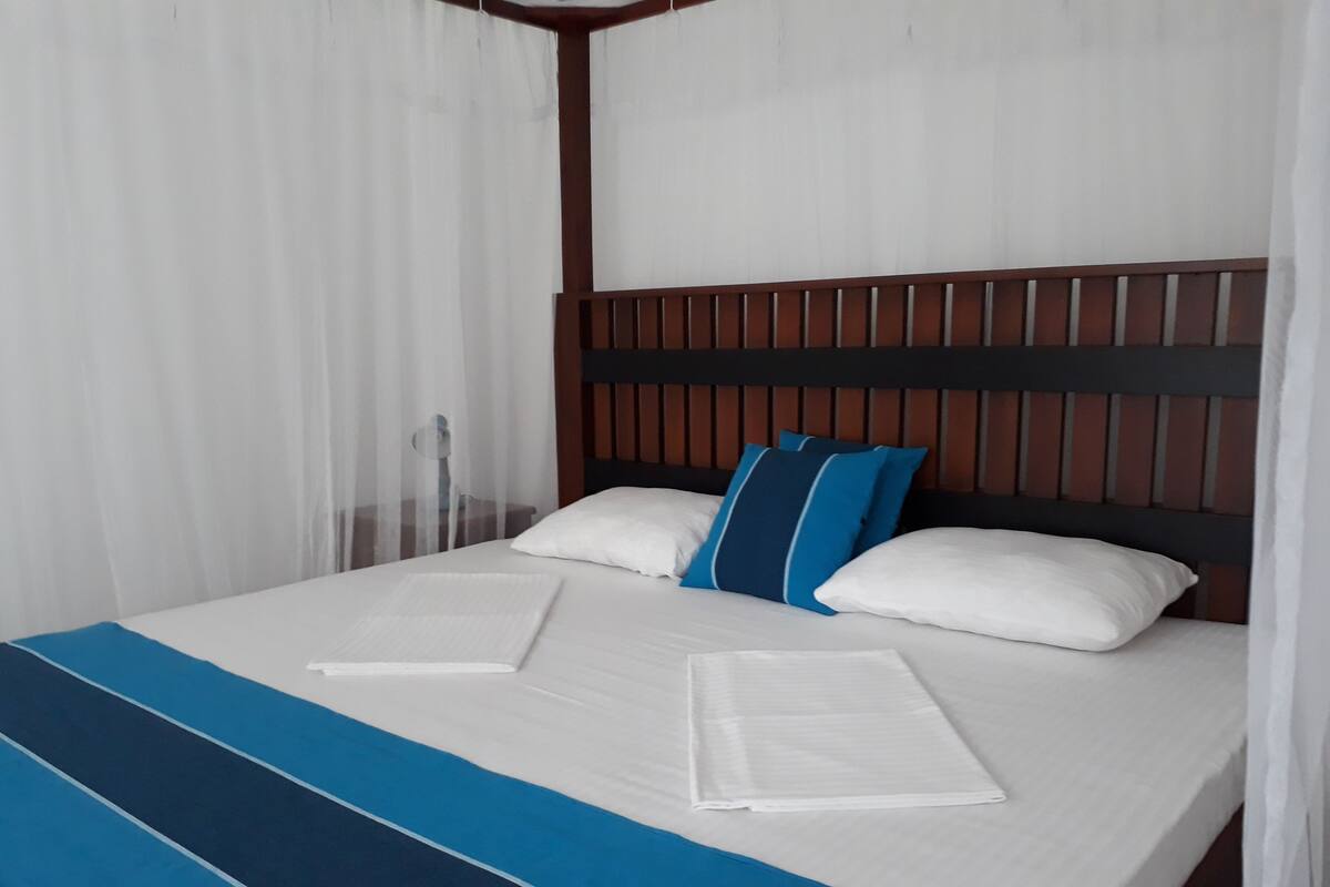 A neatly made bed with a blue and white striped bedspread, white pillows, and a wooden headboard.