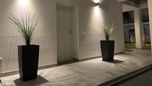 A modern building exterior with two potted plants and two wall-mounted lights. - New elegant Villa EMANUELE in Mondello Beach (Palermo)