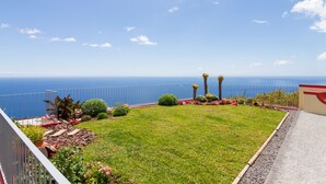 A balcony with a view of the sea, a grassy area with plants, and a railing. - Endless Blue House view of the ocean with a huge pool (Arco da Calheta)