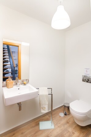 A modern bathroom with a white sink, mirror, and toilet.