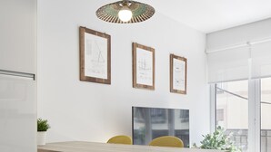 A modern kitchen with a wooden table, yellow chairs, and framed artwork on the wall. - Always Easy I San Blas (San Sebastián/Donostia)