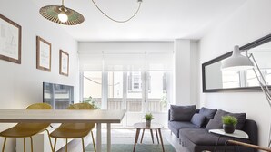 A modern living room with a dining area, featuring a sofa, chairs, a table, and a large window with a view of the city. - Always Easy I San Blas (San Sebastián/Donostia)