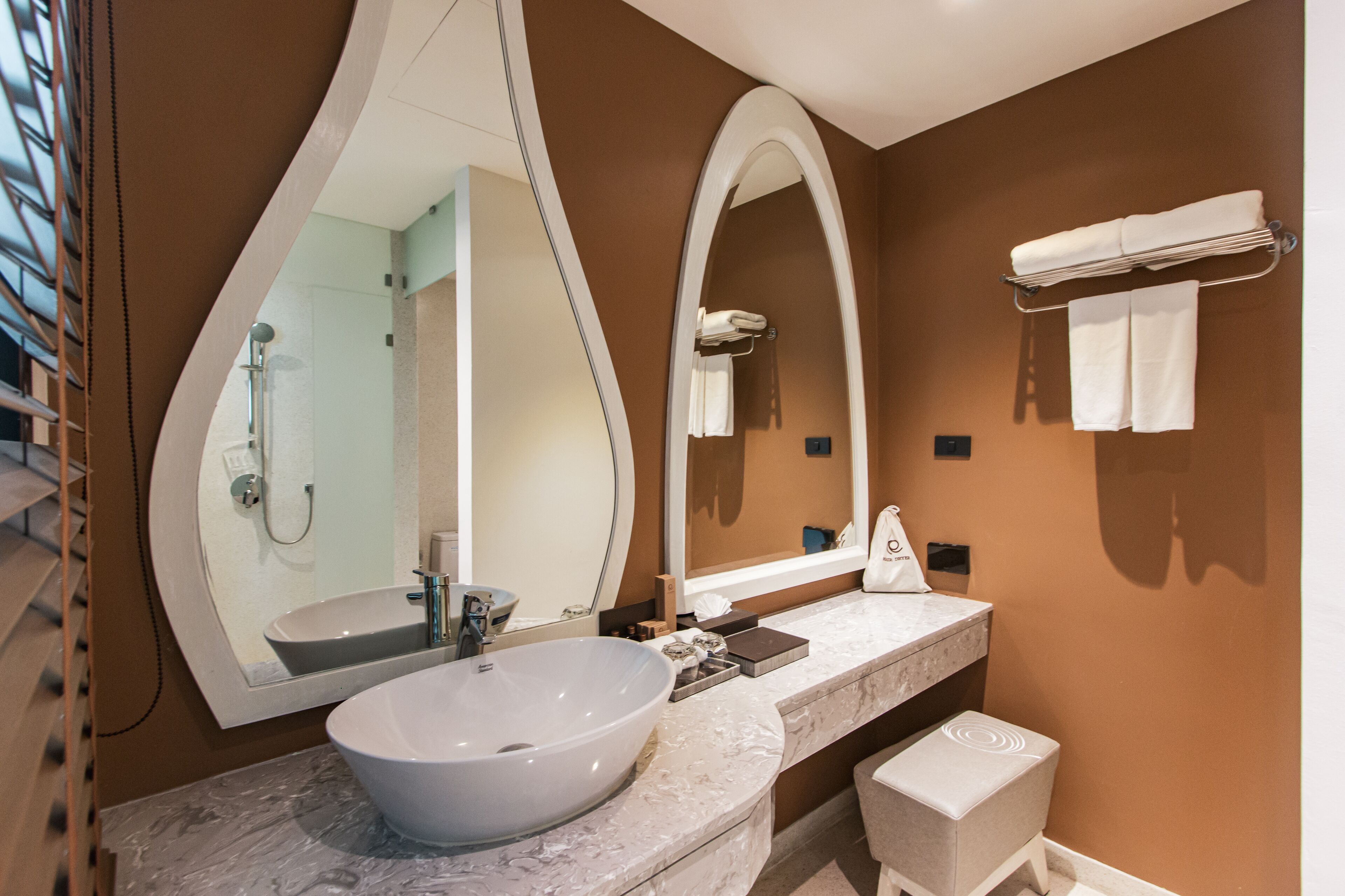 A modern bathroom with a large oval sink, a large mirror, and a towel rack.