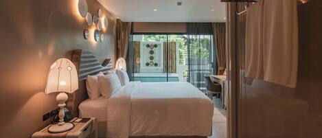 A modern hotel room with a large bed, bedside table, lamp, and a view of greenery through the window.