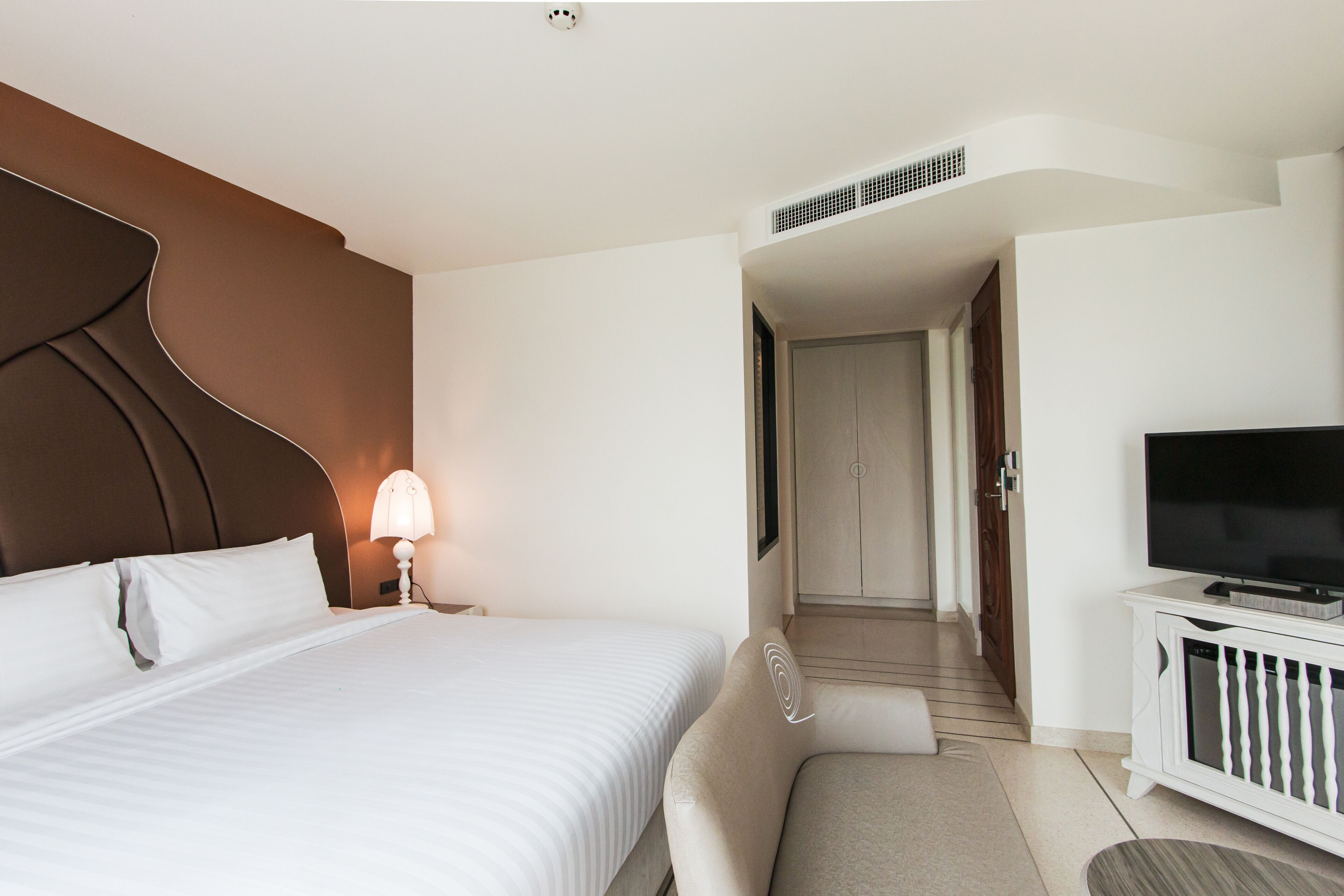 A hotel room with a large bed, a television on a cabinet, and a staircase leading to another room.