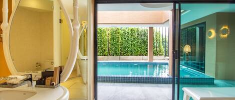 Un baño moderno con un espejo grande, un lavamanos y vistas a una piscina al aire libre.