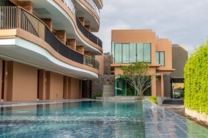 Un hotel moderno con piscina, balcones curvos y una arquitectura que combina vidrio y ladrillo.