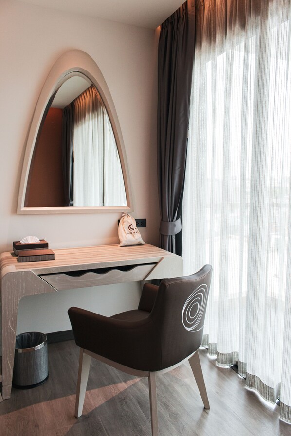 Un dormitorio moderno con cama, escritorio, silla, espejo y ventana con cortinas.